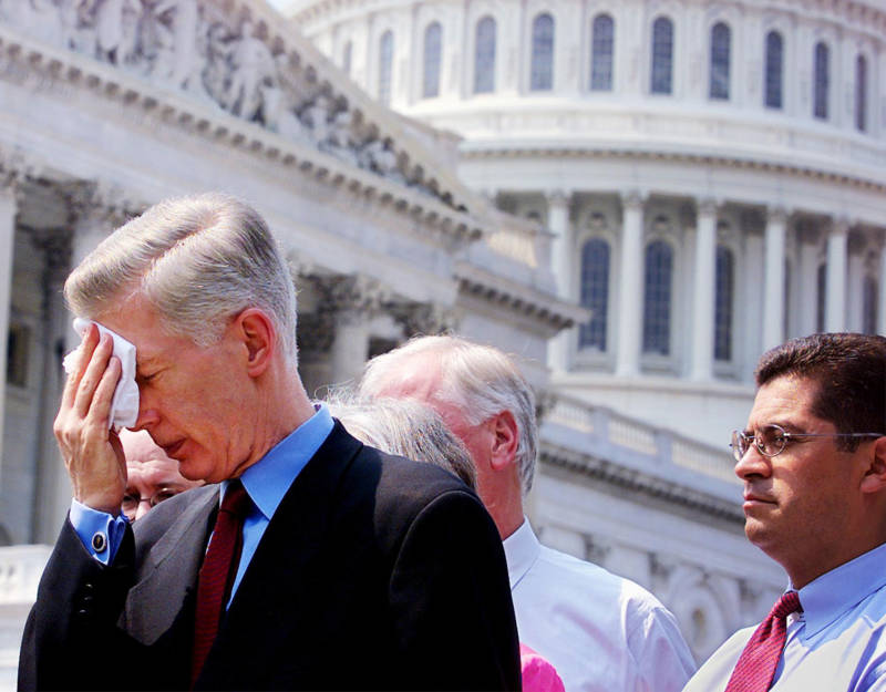 Gov. Gray Davis (L) wipes his brow after delivering a press statement on Capitol Hill, Washington, DC, after testifying in Congress on June 20, 2001 as then-Rep. Xavier Becerra (R), D-CA, listens. Davis blamed a Republican-led energy regulatory agency for not helping during California's energy crisis.