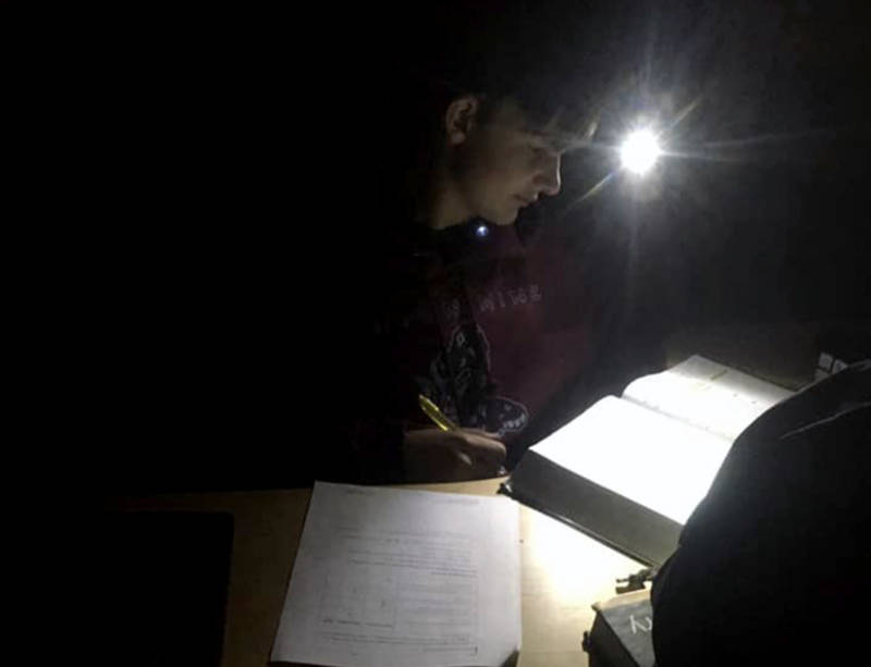 Alecxander Cooper, 13, of Shingle Springs, does homework by headlamp in one of PG&E's power shutoffs in October.