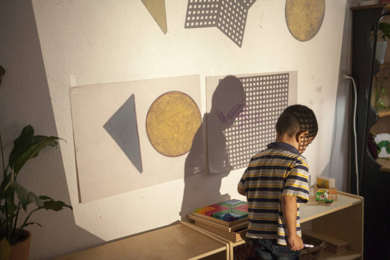 A child walks through shapes projected on a wall at "The Nest" in Tijuana.