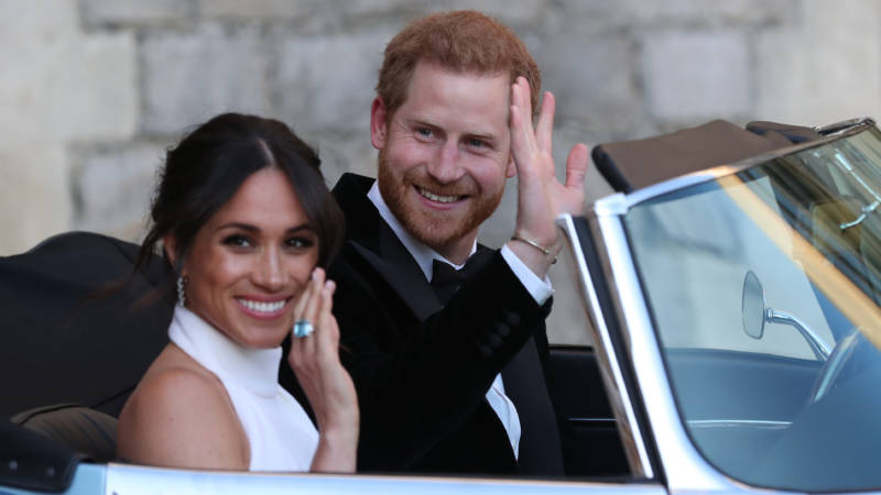 Meghan Markle, the Duchess of Sussex, and Prince Harry wave as they leave Windsor Castle en route to their post-wedding reception.