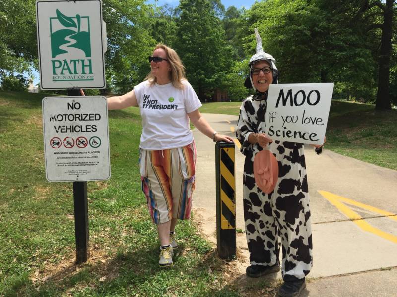 Two women stand along the side of the route of the Atlanta March for Science.