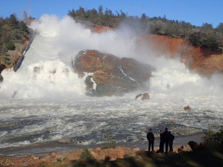 A Cal Fire team watches water surge down and around the collapsed main spillway at Oroville Dam on February 11.