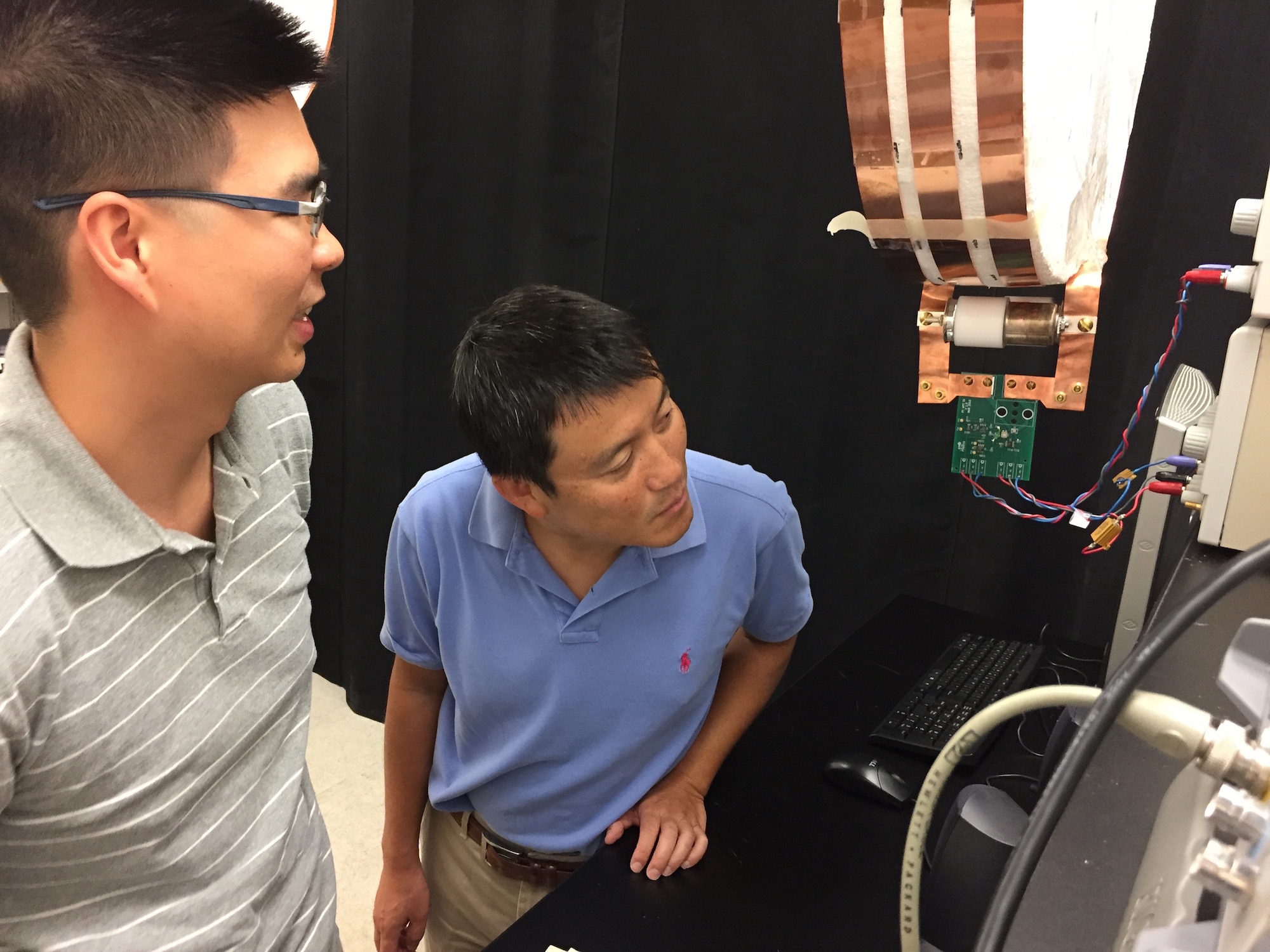 Electrical engineers Sid Assawaworrarit (left) and Shanhui Fan examine their demonstration apparatus for dynamic charging in their lab at Stanford.