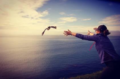 A woman releases a bird over the ocean