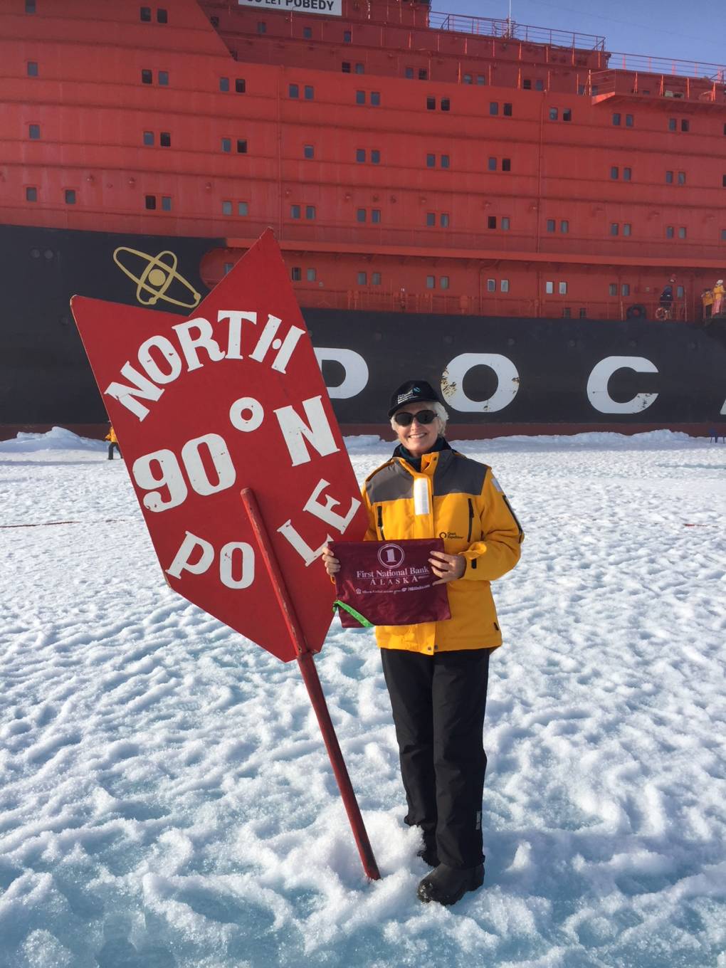 A woman stands next to a sign reading 'North Pole'.