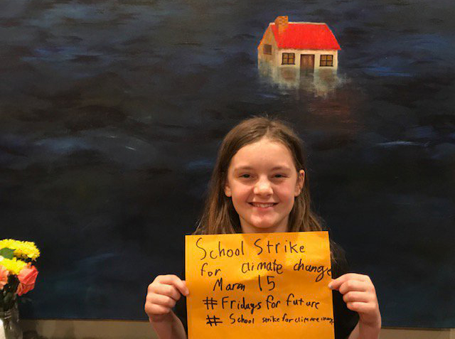 Fifth grade climate activist holding sign.