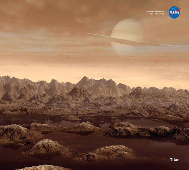 Artist concept of the surface of Titan, its high and rugged mountains, surface liquid methane, atmosphere, and Saturn in the hazy sky above.