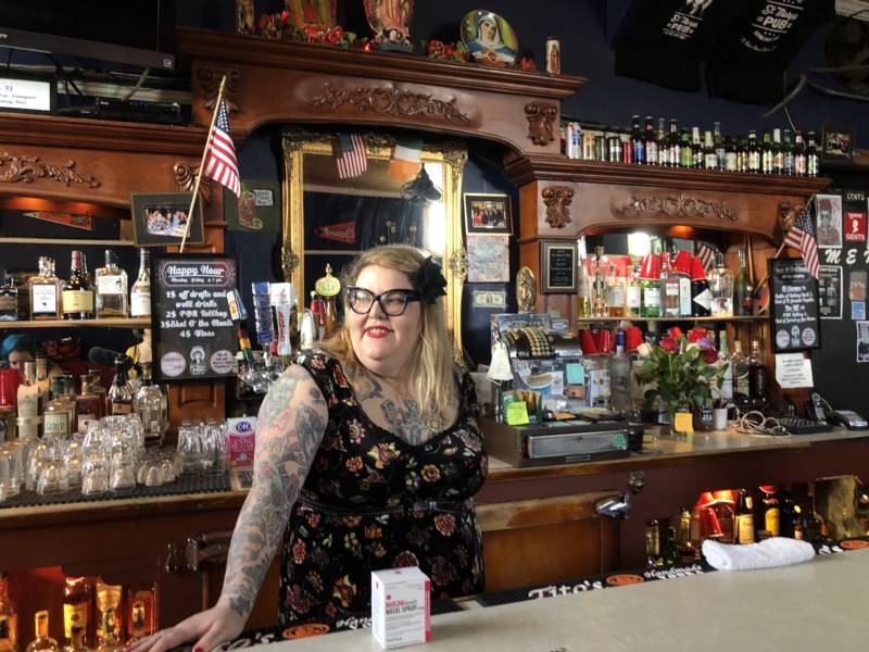 Amy Rothbauer, a bartender at St. Marys Pub, poses with the box of Narcan that she keeps behind the bar, next to the first aid kit.